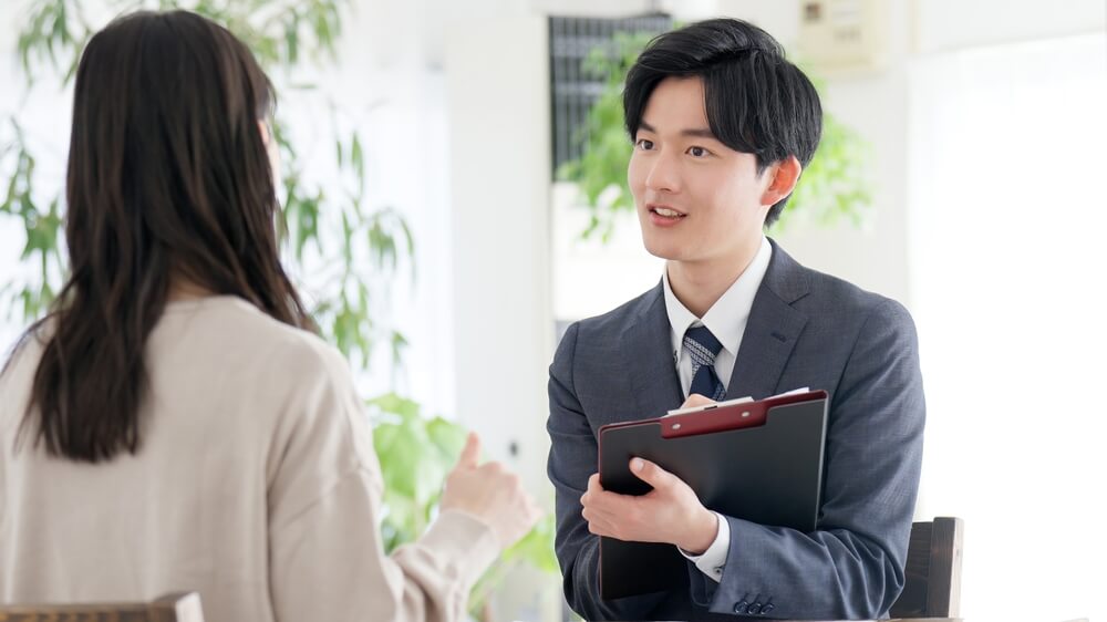 女性に説明するスーツ姿の男性スタッフ