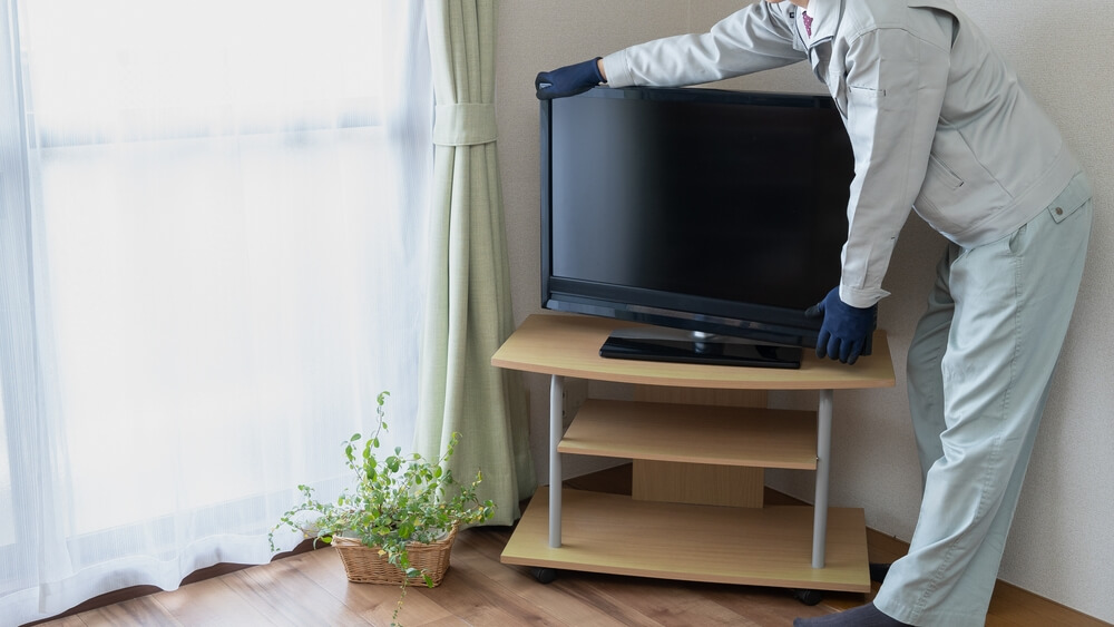 テレビを移動させる作業員と家具