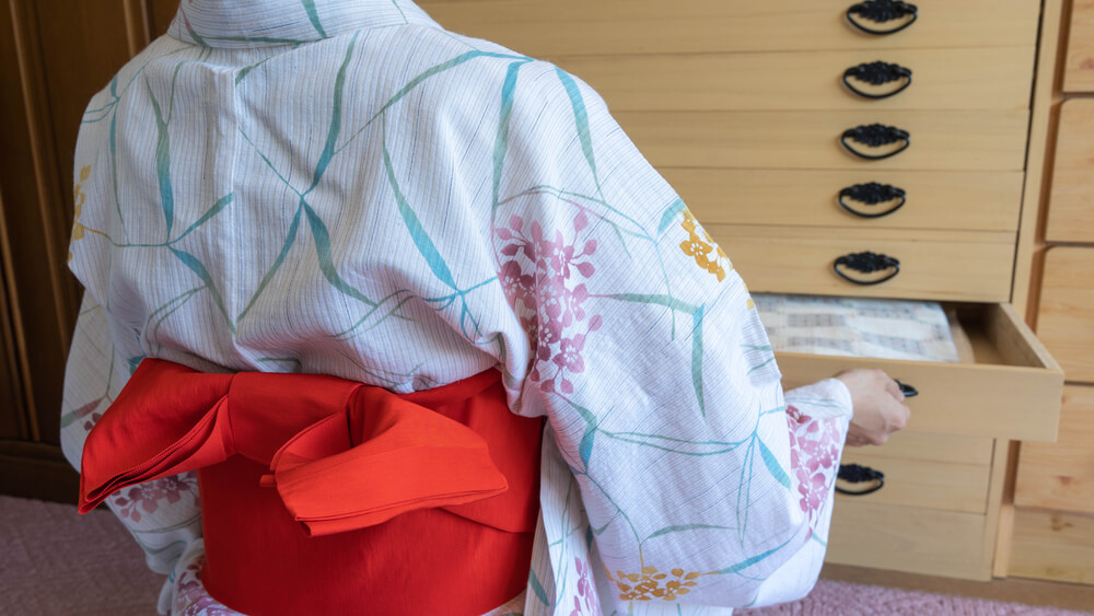 着物姿の女性が桐箪笥を開ける様子