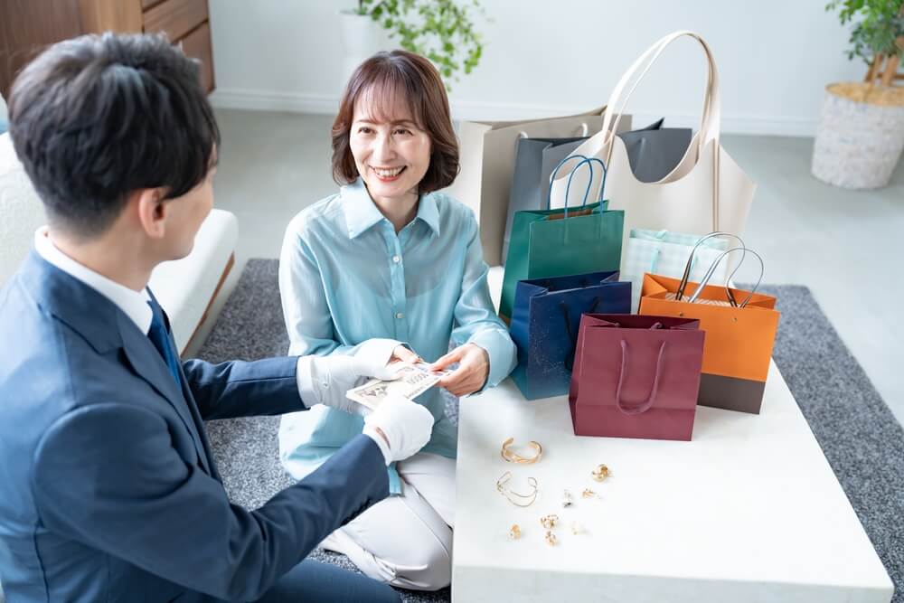 笑顔で現金を受け取る女性と査定士のやり取り