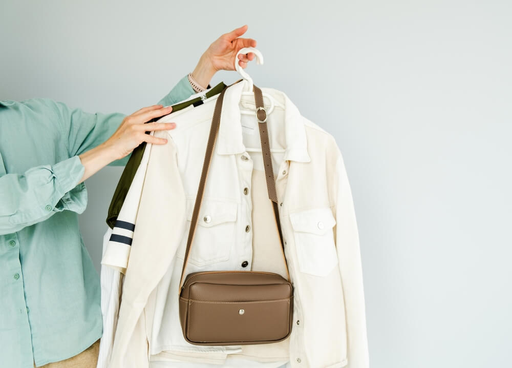 ジャケットとバッグを手に取る女性の上半身