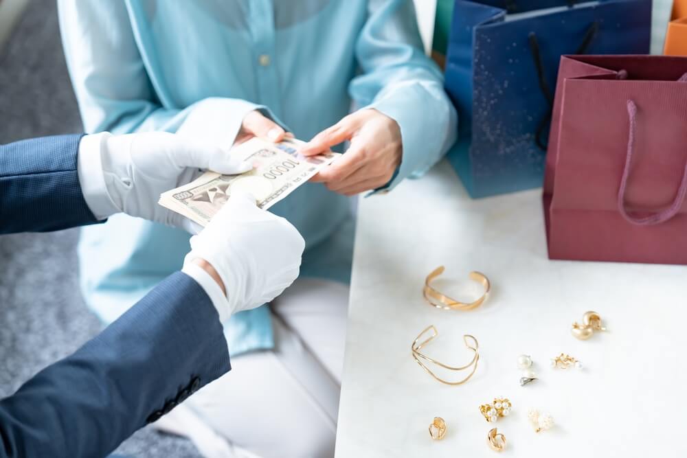査定額を受け取る女性とジュエリーのテーブル